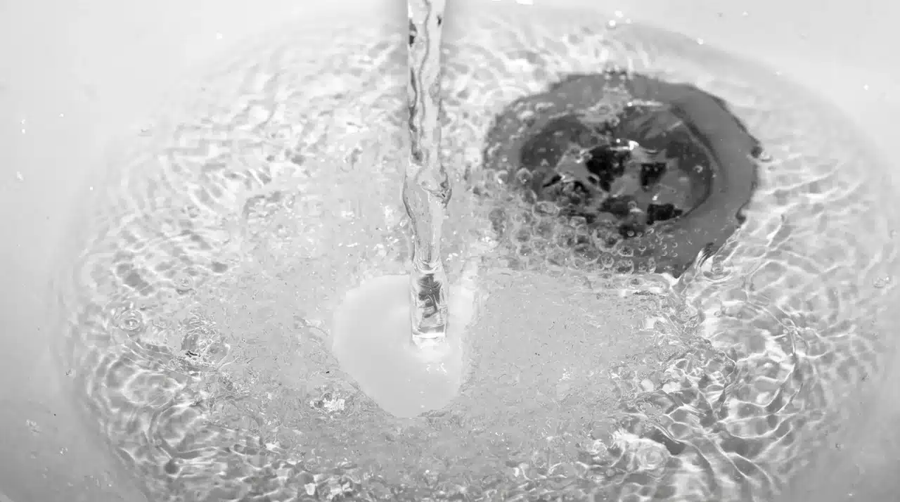 Standing water in a bathroom sink before drain unclogging, showing a common household plumbing problem