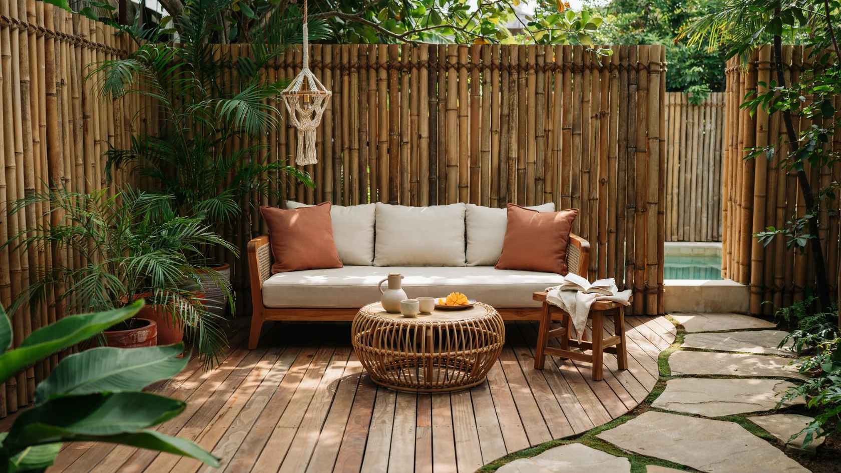 Bamboo privacy fence surrounding a cozy patio seating area with tropical plants and wood decking