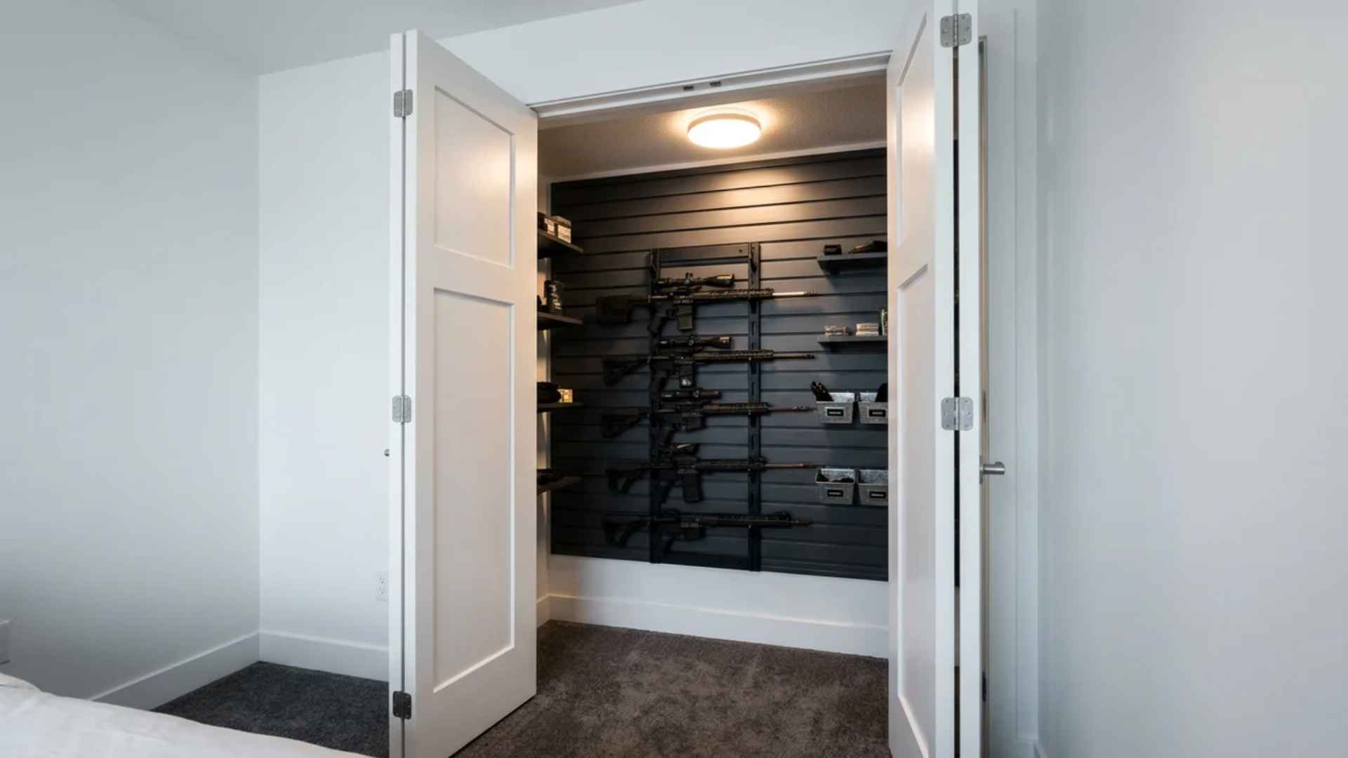 Converted closet gun room with slatwall storage, rifles, and motion lighting behind closet doors