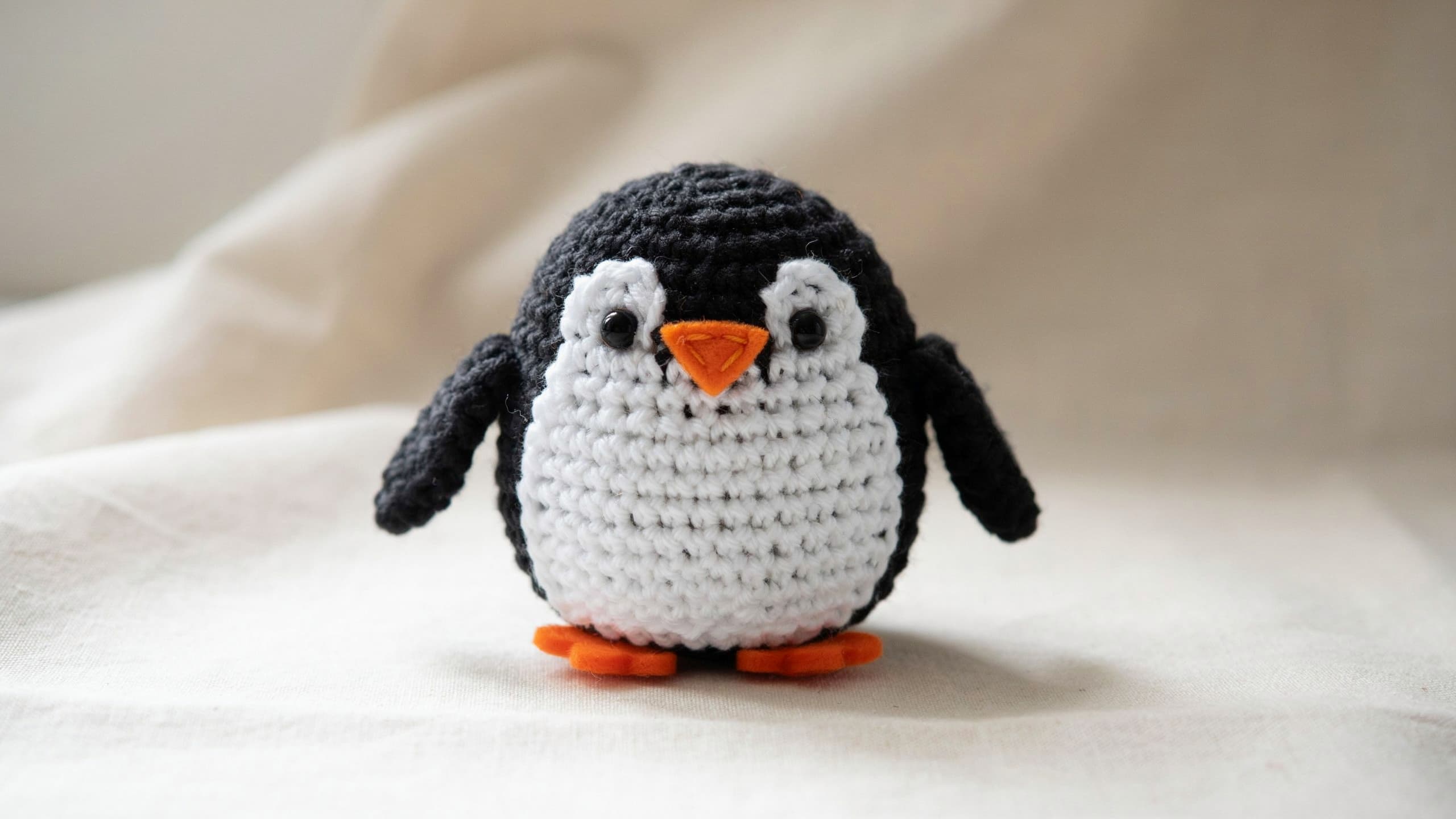 Black and white crochet penguin with orange beak centered