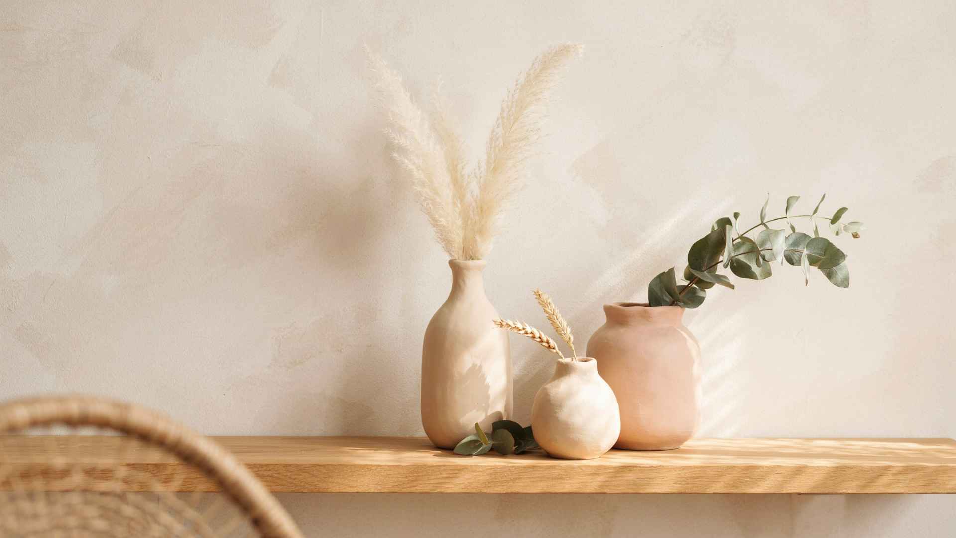Clay vases with dried flowers on minimalist shelf