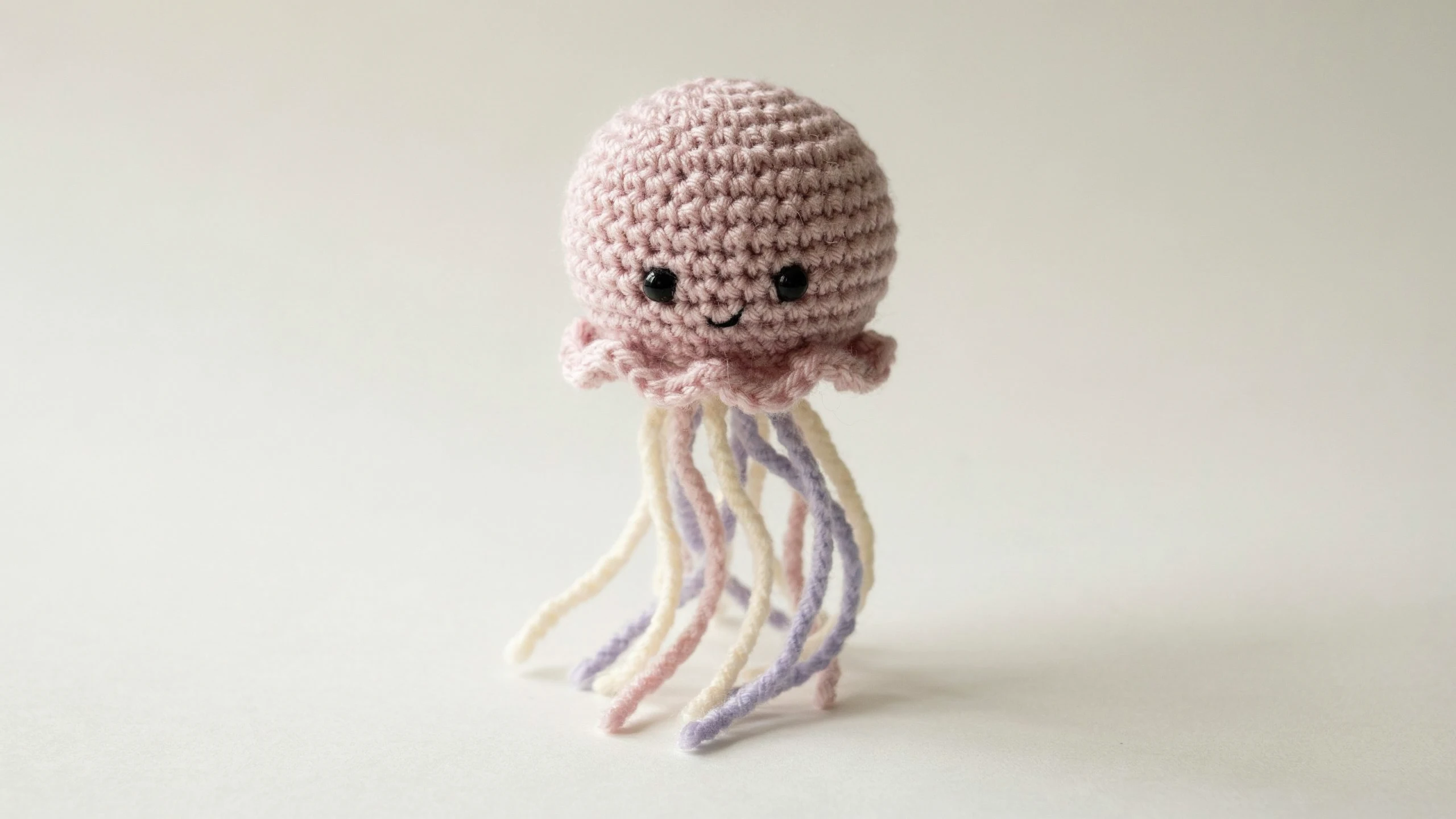 Crochet jellyfish with domed body and soft yarn tentacles centered