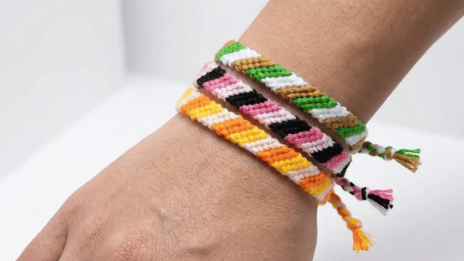 Three woven friendship bracelets with diagonal stripes worn on a wrist.