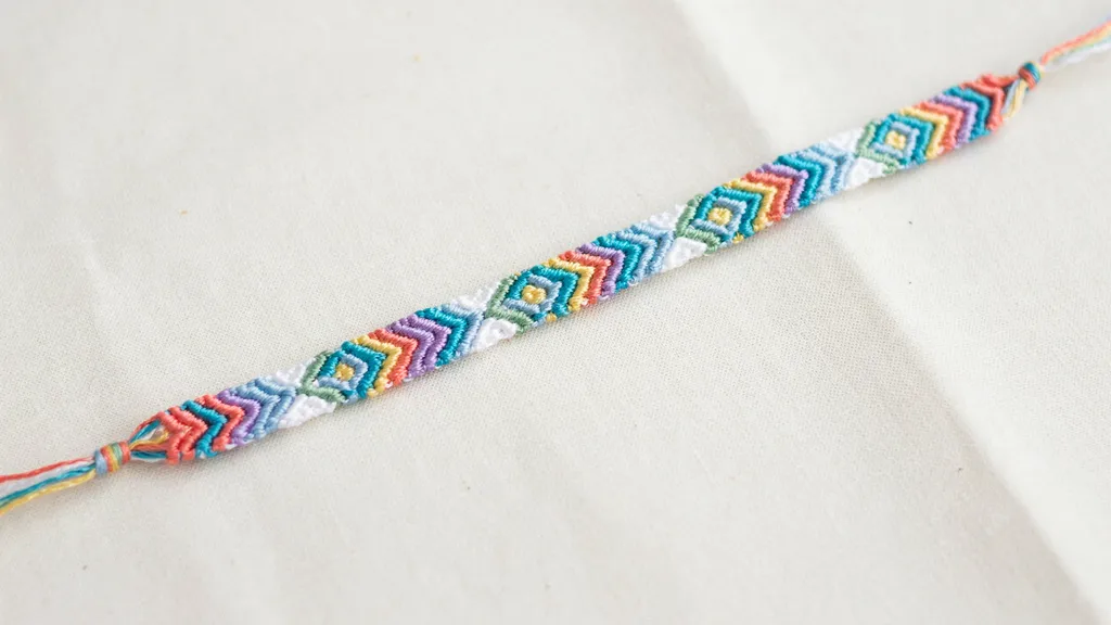Friendship bracelet with colorful diamond motifs and geometric woven details on fabric.