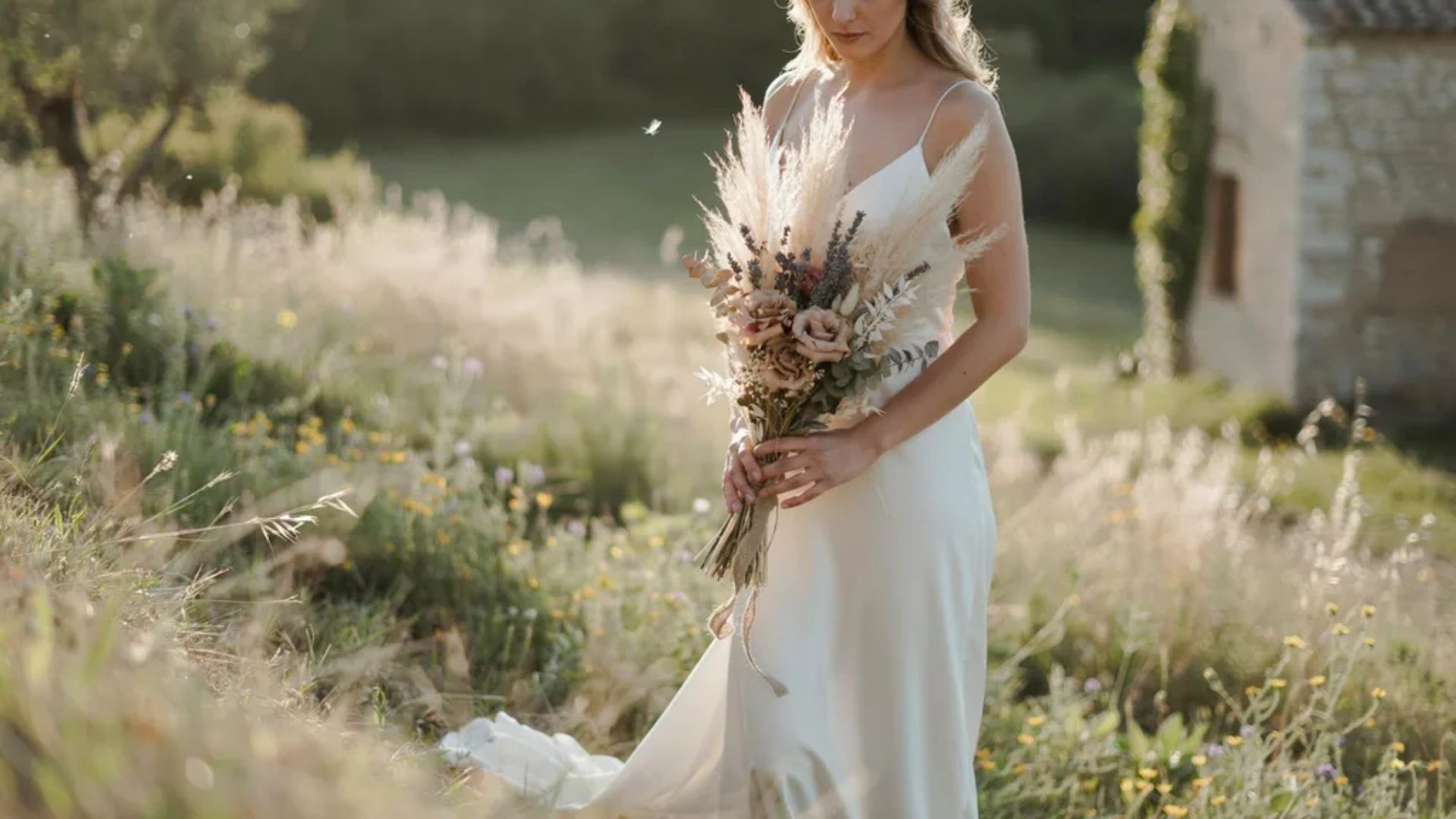 Dried wedding bouquet with pampas grass lavender and preserved roses held by bride in rustic wedding setting