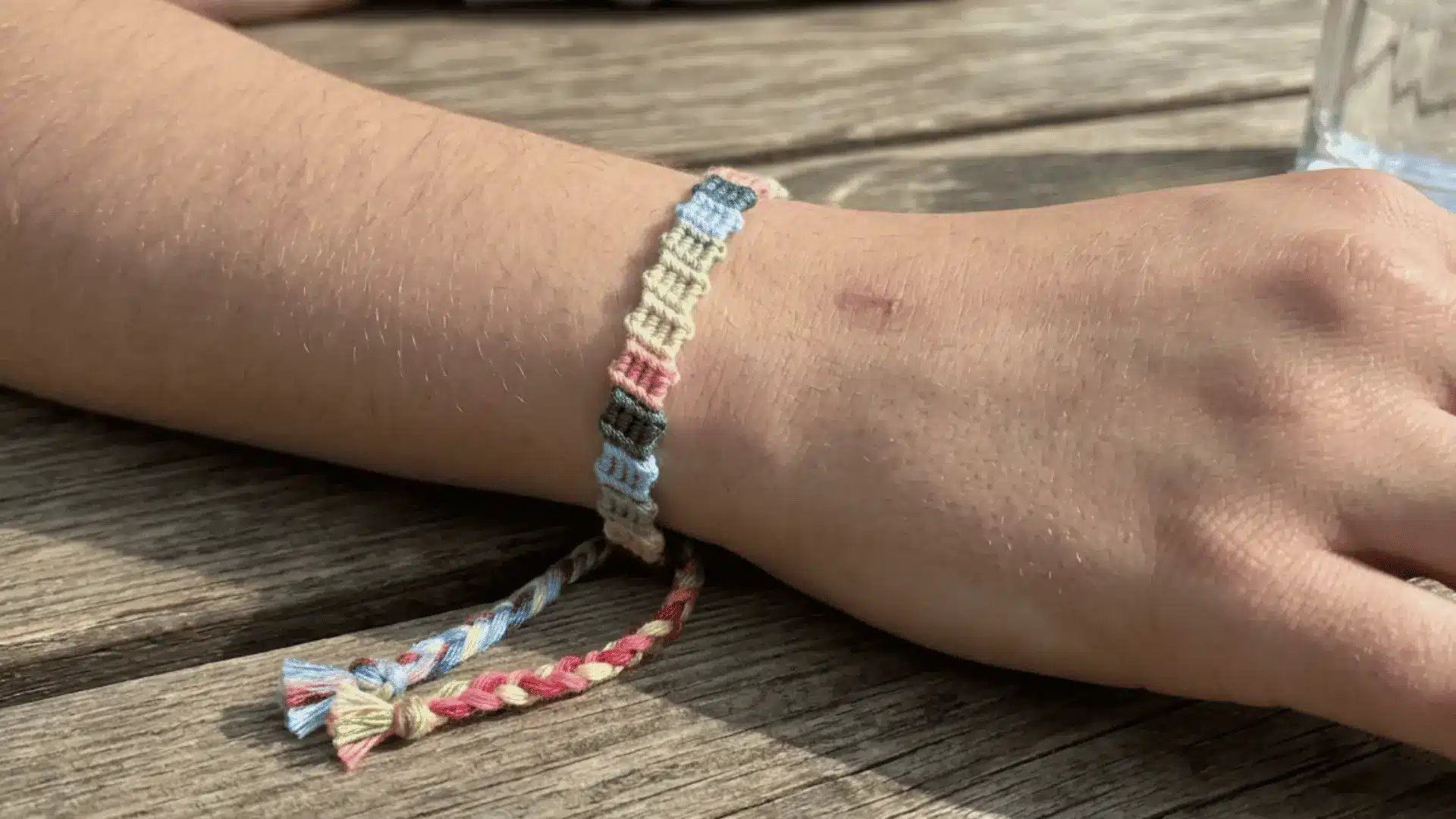A multi-colored woven flip-flop friendship bracelet worn on a wrist.