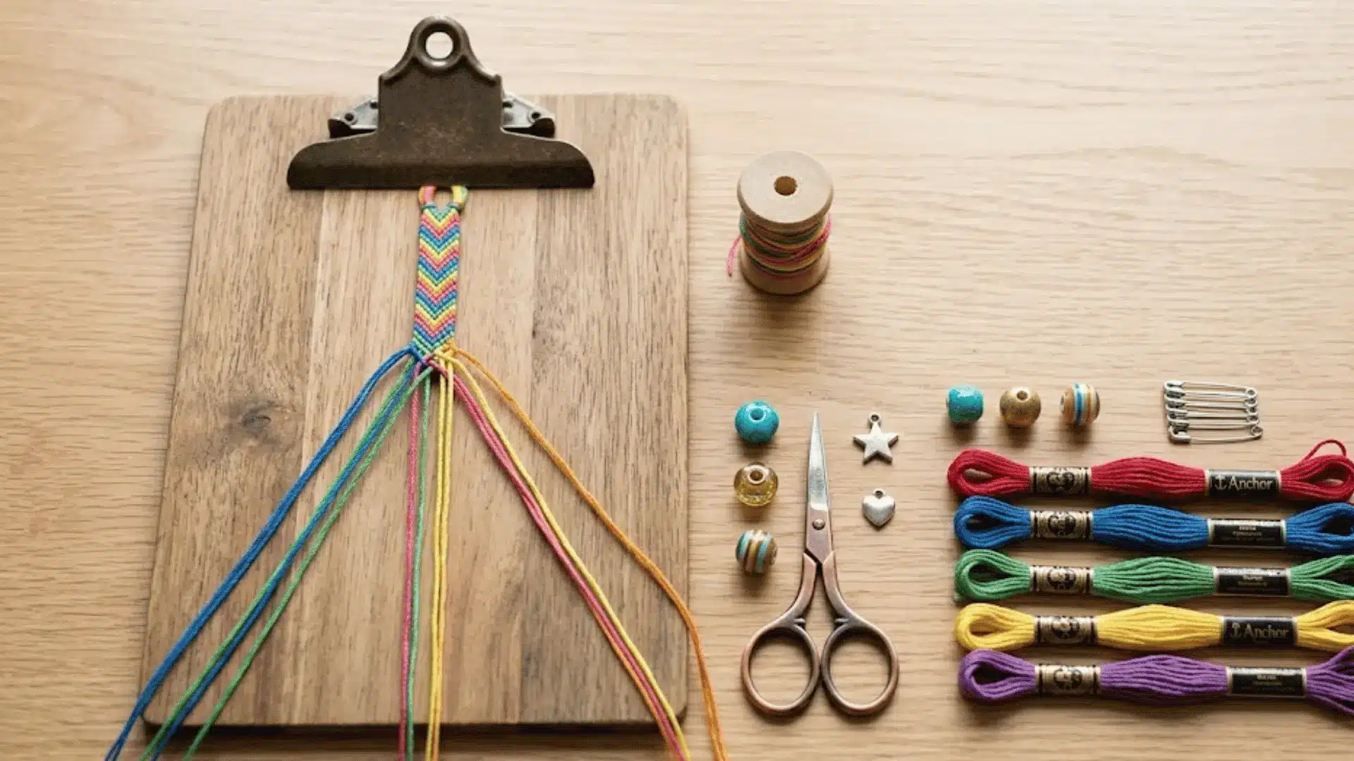 Embroidery floss, beads, and tools arranged beside a partially finished handmade string bracelet.