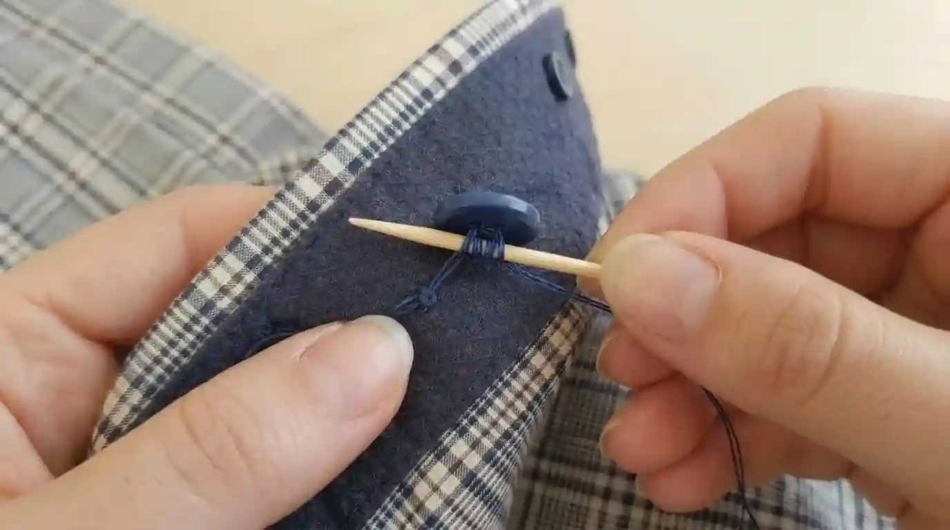 A close-up of hands creating a button shank using thread.