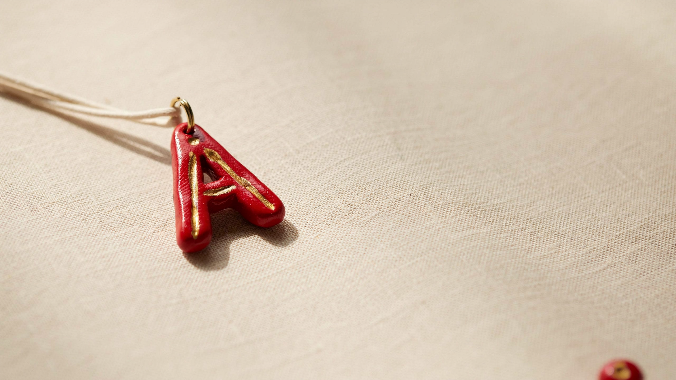 Handmade clay initial letter keychain shaped from cut alphabet form, with smooth edges and hanging hole, designed for personalized accessory or gift use