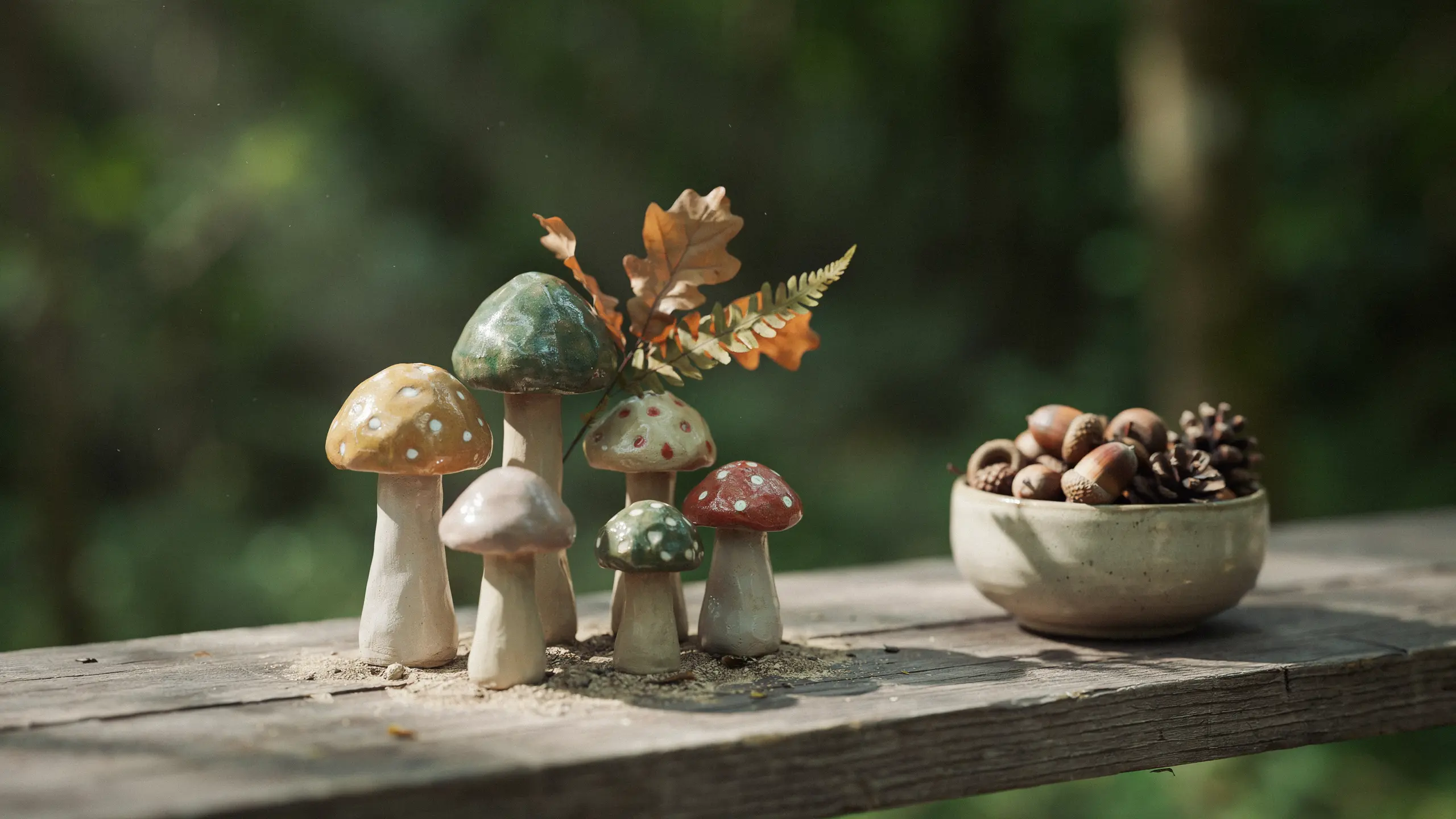 Handmade clay mushrooms with painted caps and earthy tones displayed on wooden shelf.