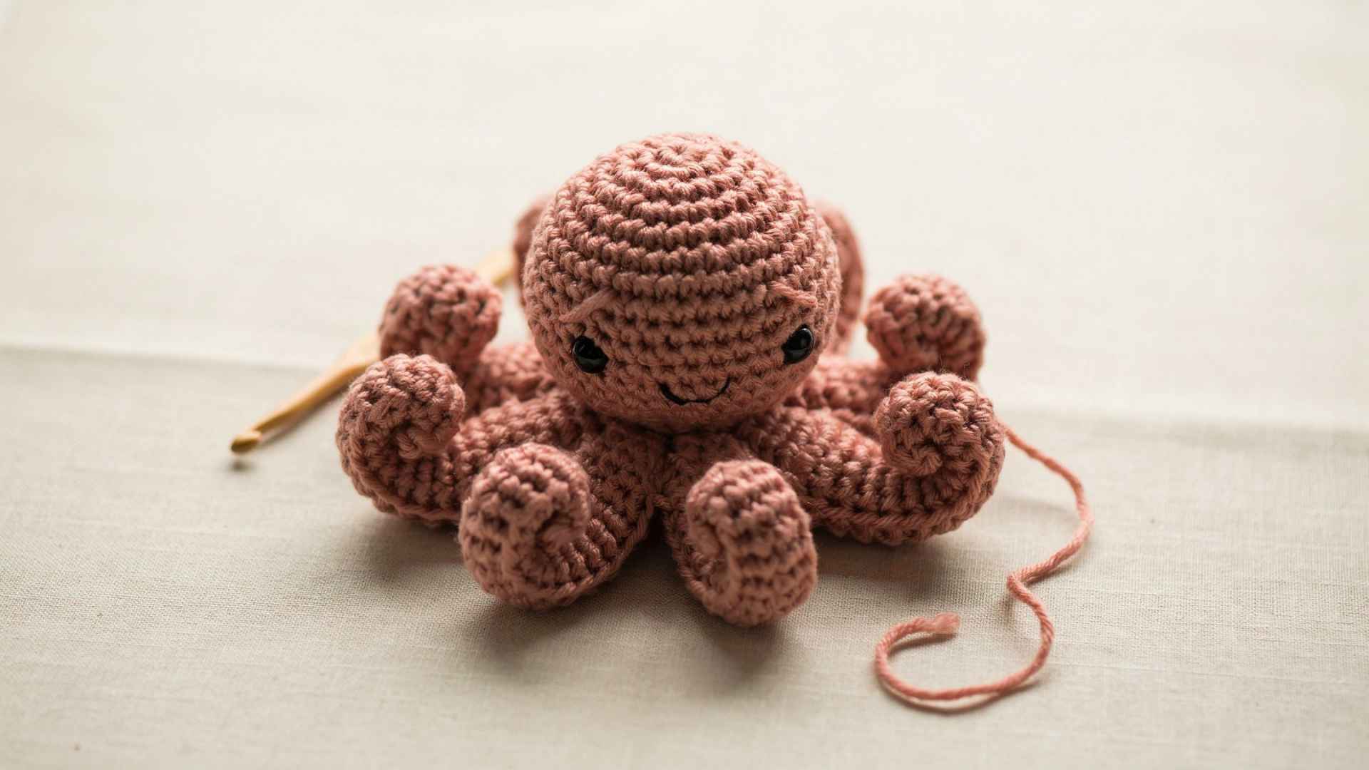 Completed crochet octopus with curled tentacles simple beginner amigurumi on neutral fabric background soft lighting