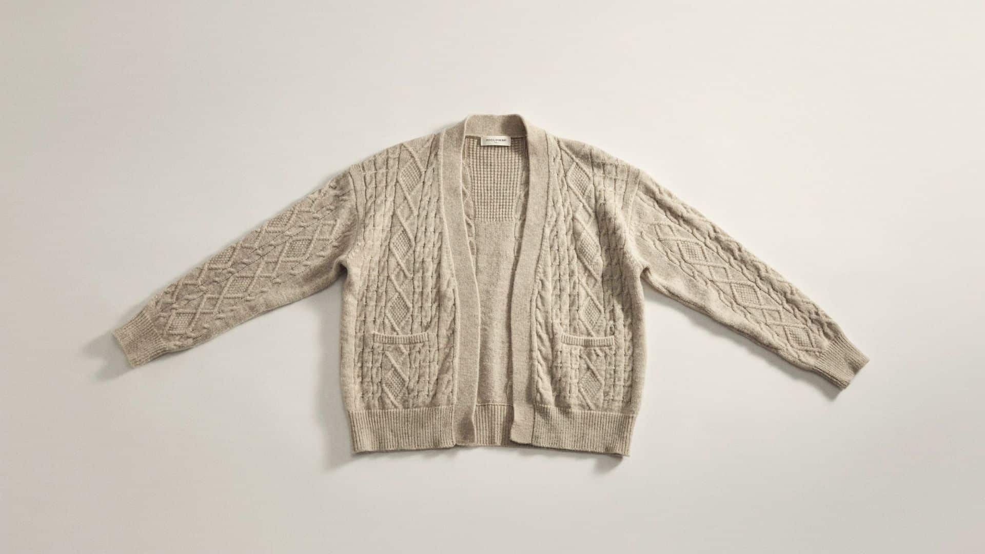 Beige wrap-style knitted cardigan with a tie waist, balloon sleeves, and soft textured fabric displayed on a neutral background.