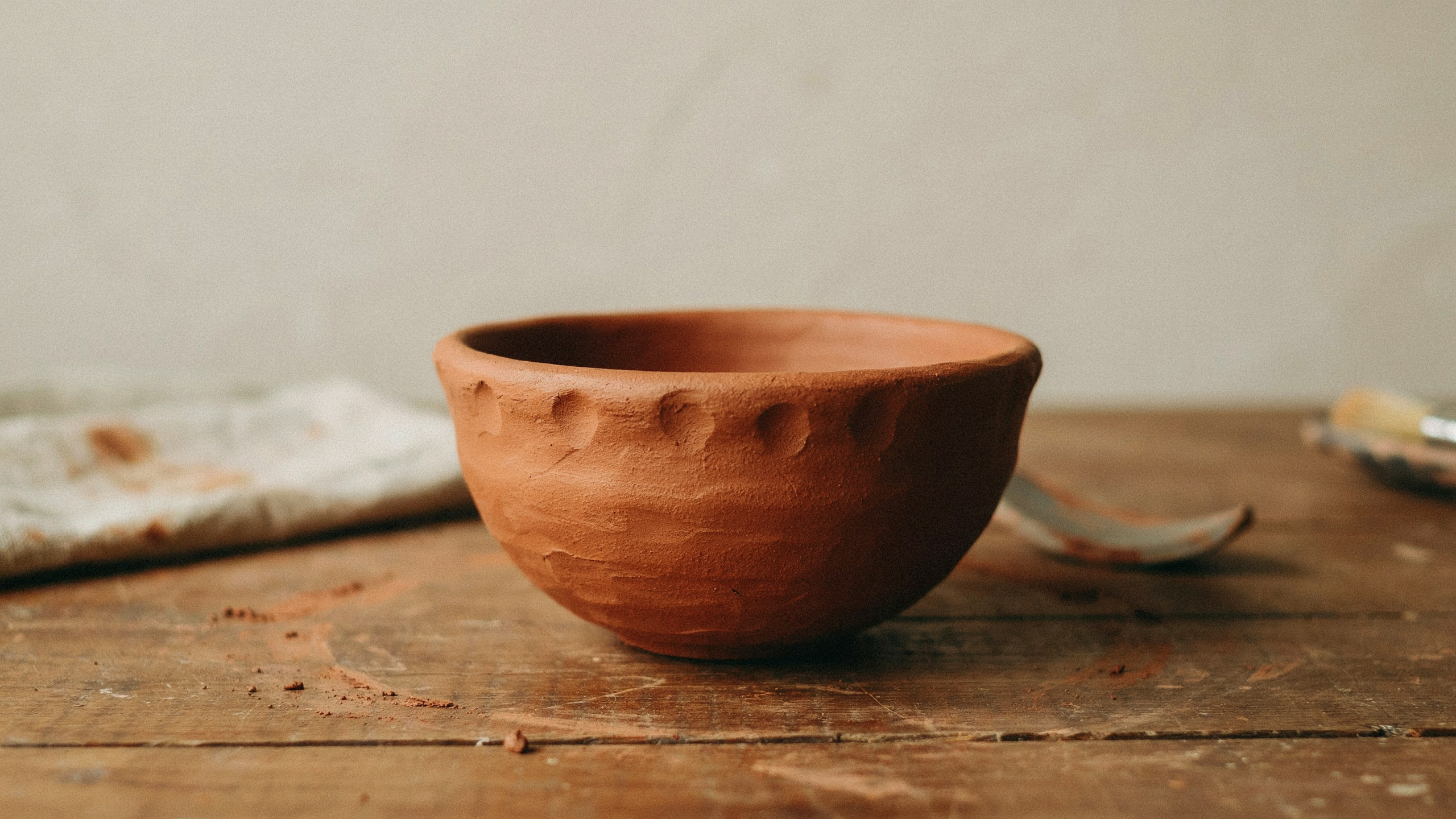 Simple handmade clay pinch pot bowl formed using thumb pressed technique, with rounded walls and smooth rim edges, designed for beginner pottery practice