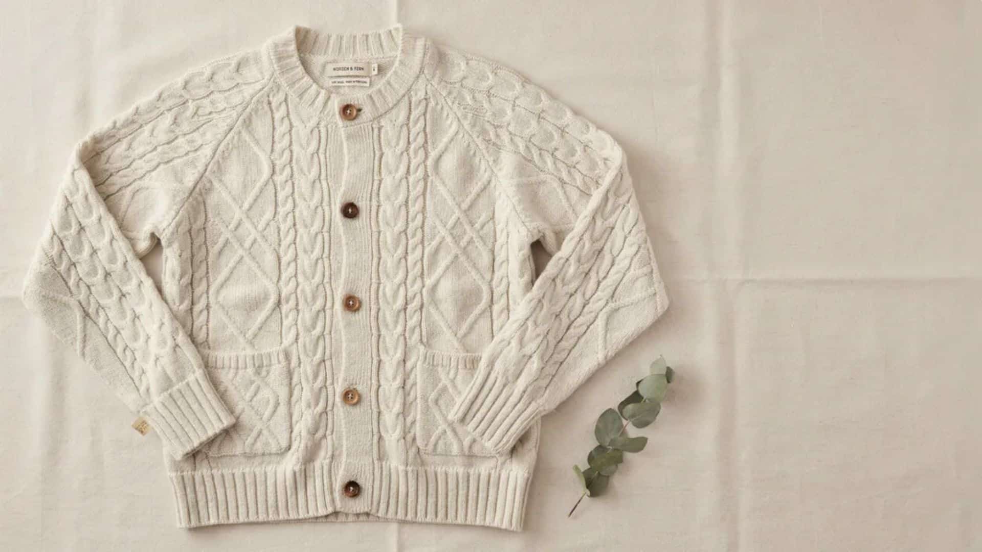 Neutral beige open-front cable knit cardigan with textured pattern, long sleeves, and ribbed hem displayed on a plain background.