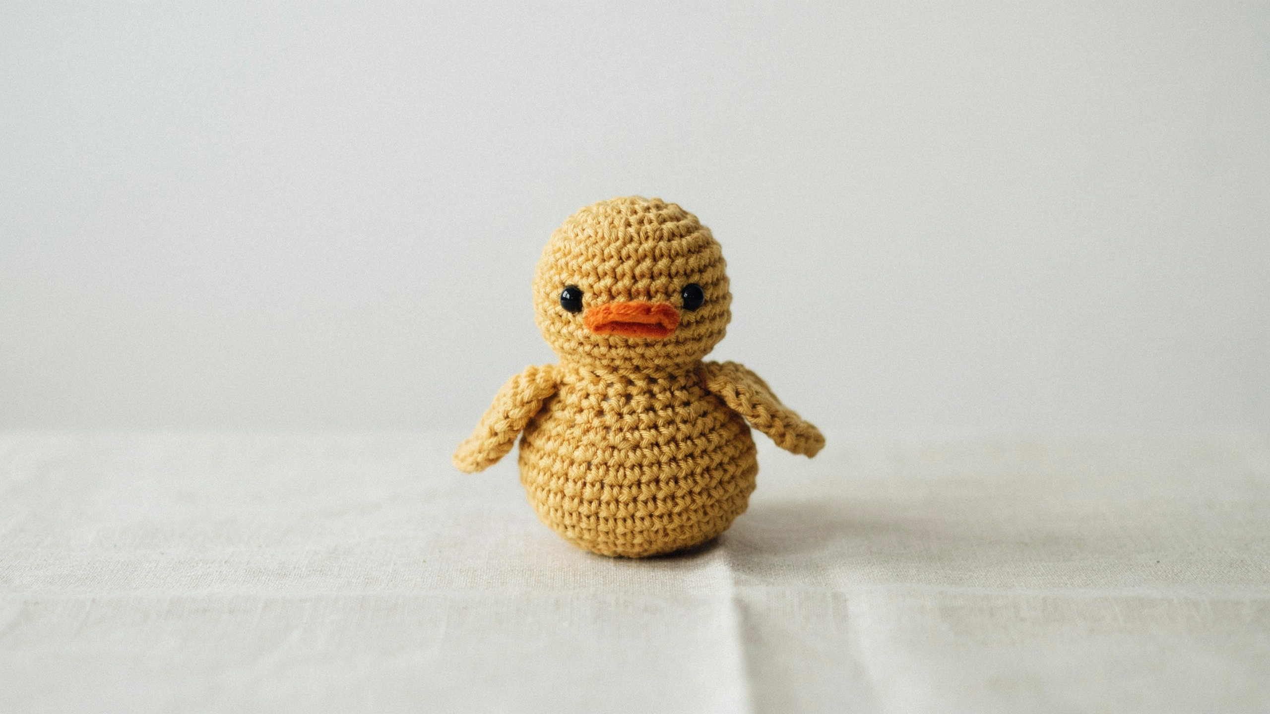Round yellow crochet duck with flat orange bill centered