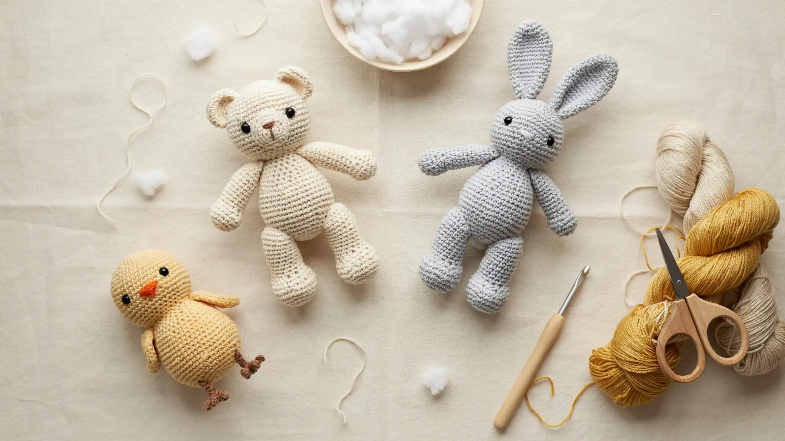 Small crochet animals made with yarn and a hook, showing simple amigurumi shapes with separate parts like head, body, and limbs, alongside basic tools used to make them.
