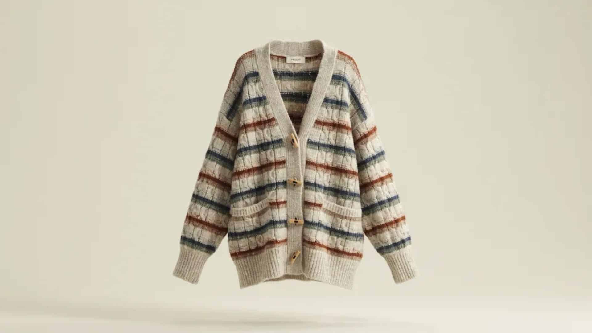 Beige cropped cable knit cardigan with button front closure and ribbed hem displayed on a neutral fabric background.