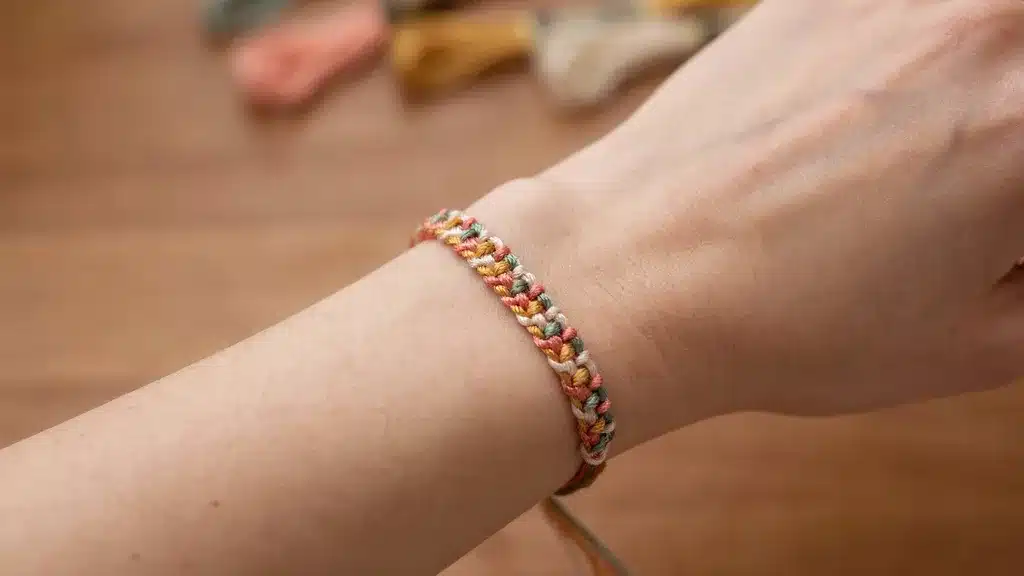 Finished friendship bracelet on a wrist with neatly secured and tucked string ends.