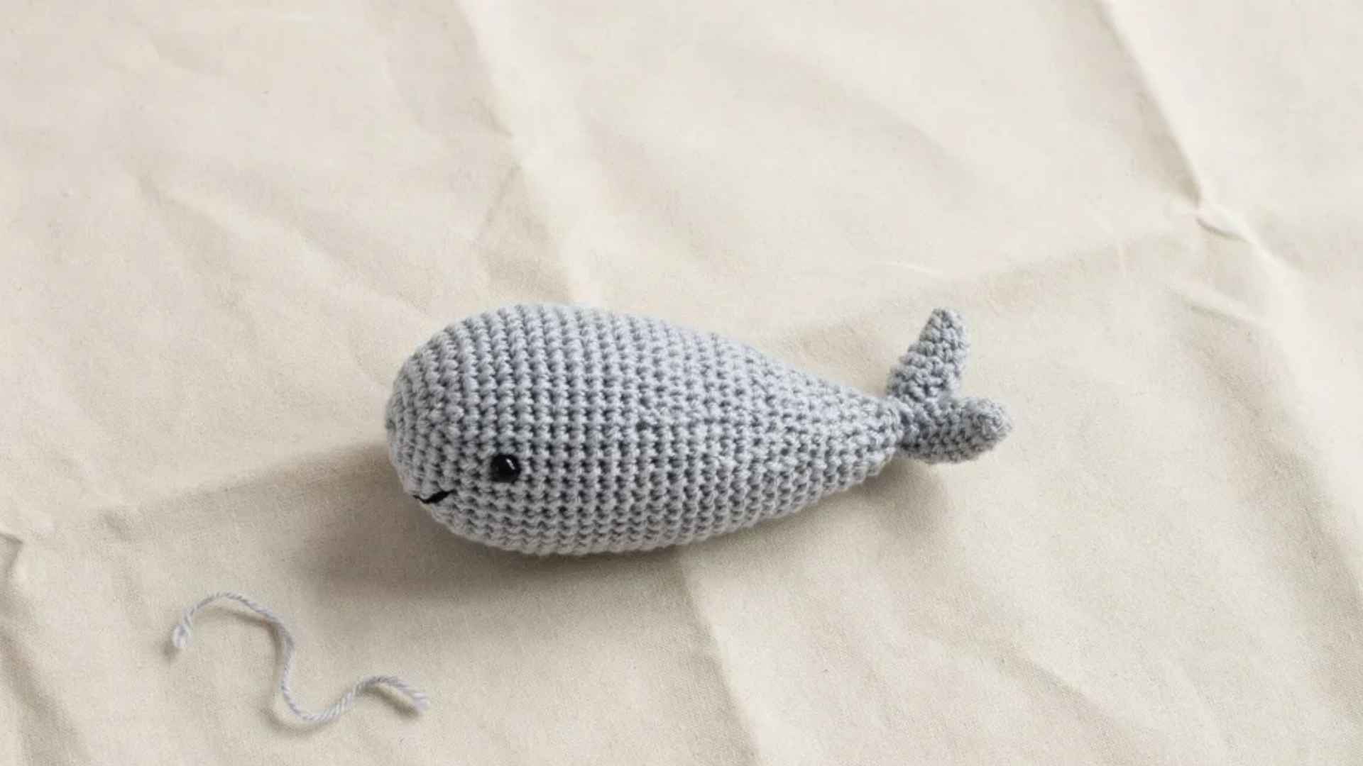 Simple crochet whale amigurumi oval body seamless beginner project on soft beige background with warm lighting