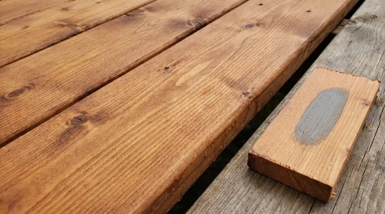 Cedar deck boards with warm reddish grain and a semi-transparent stain swatch comparison beside them