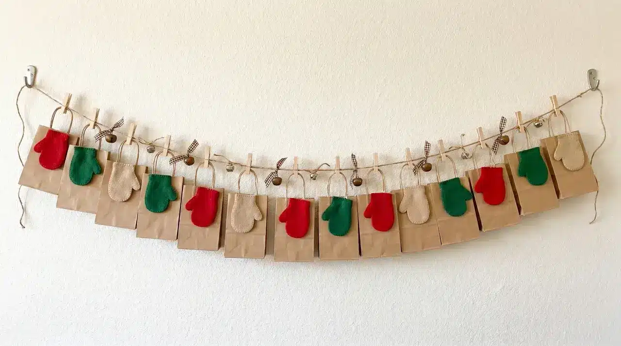 DIY advent calendar with hanging paper bags and mini mittens clipped to twine on a wall