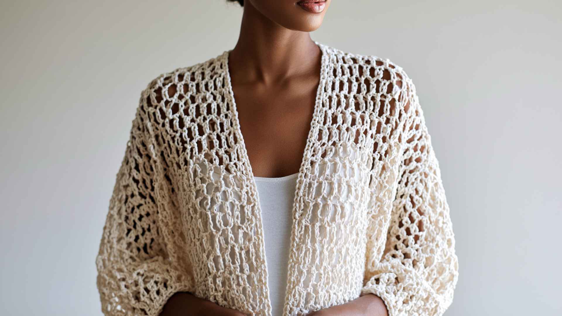 Waist-up model wearing an airy mesh crochet summer cardigan.