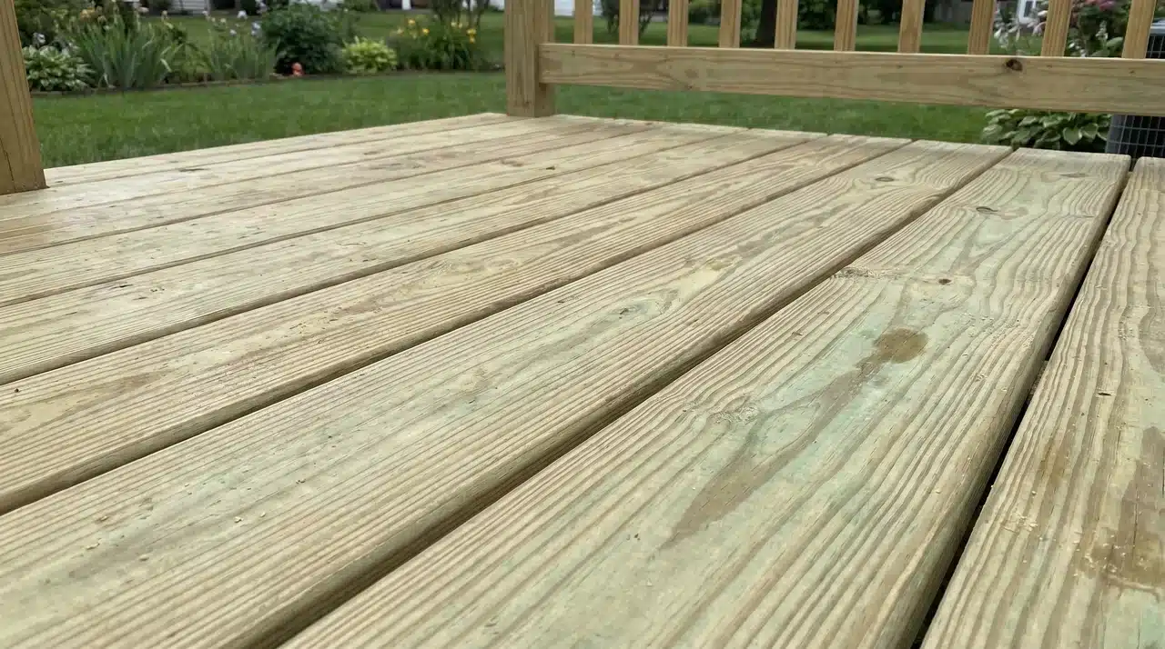 Freshly installed pressure-treated wood deck boards with natural green tint before staining