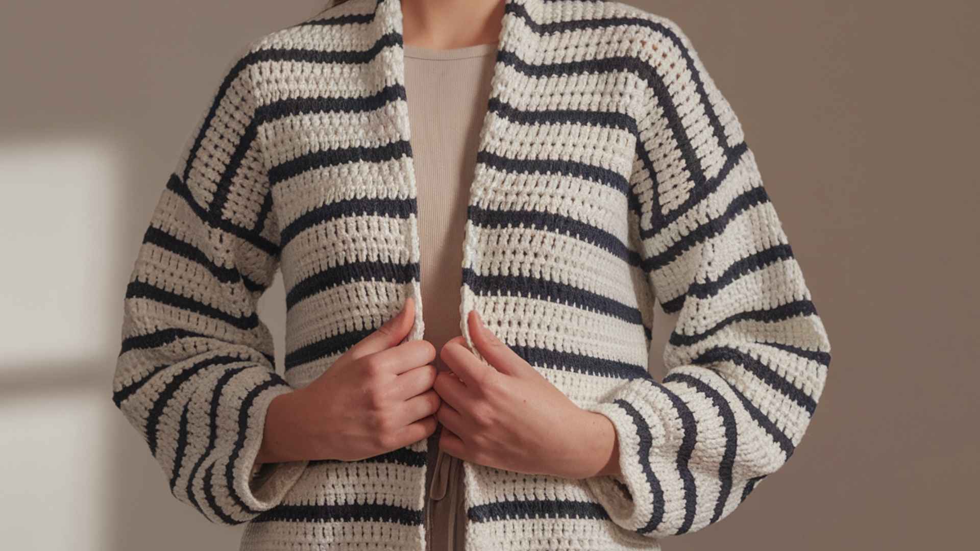 Waist-up model wearing a striped longline crochet cardigan.