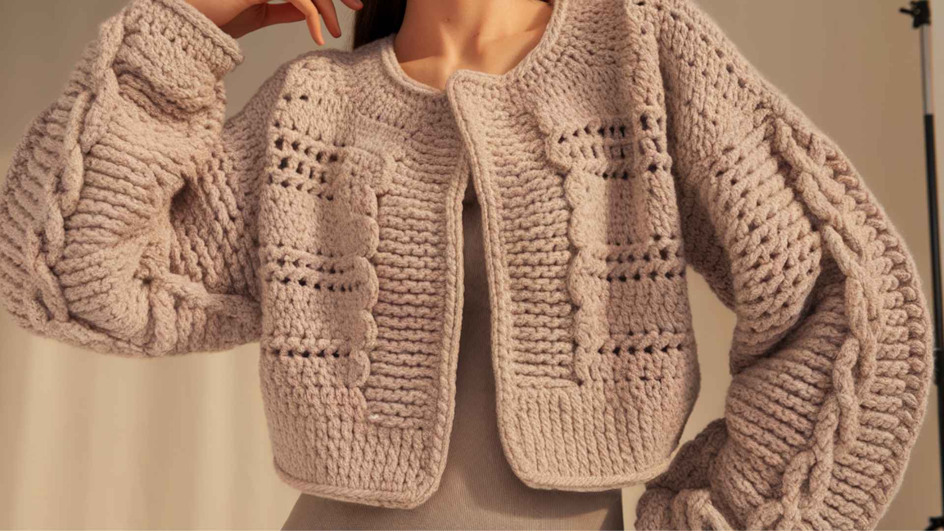 Waist-up model in a bulky yarn crochet cardigan with thick textured stitches.